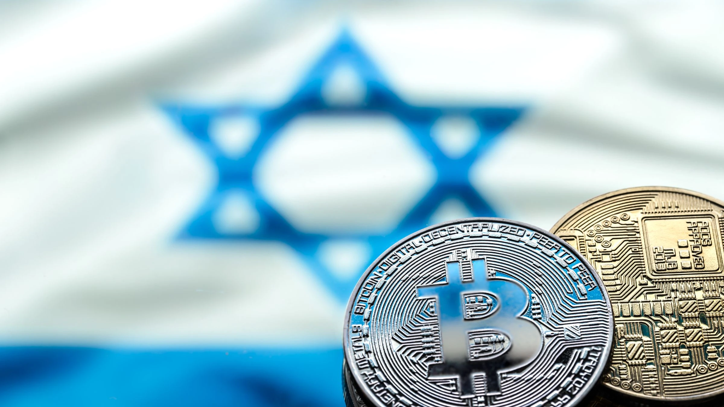 Bitcoin and digital cryptocurrency coins displayed with a blurred Israeli flag in the background