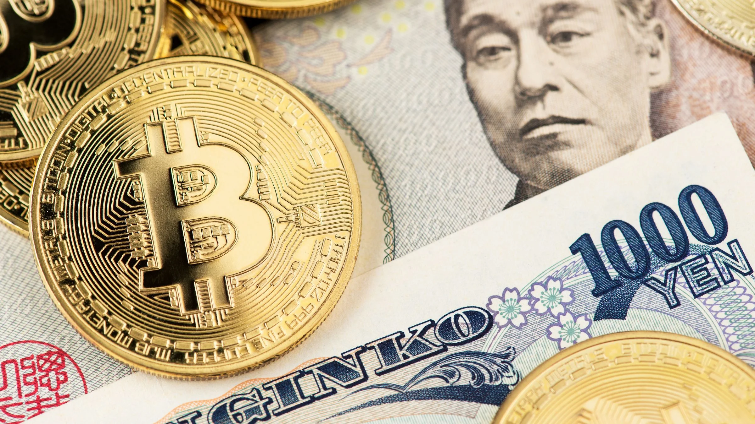 Golden Bitcoin coins placed on top of Japanese yen banknotes, including a 1000 yen note, in a close-up photograph.