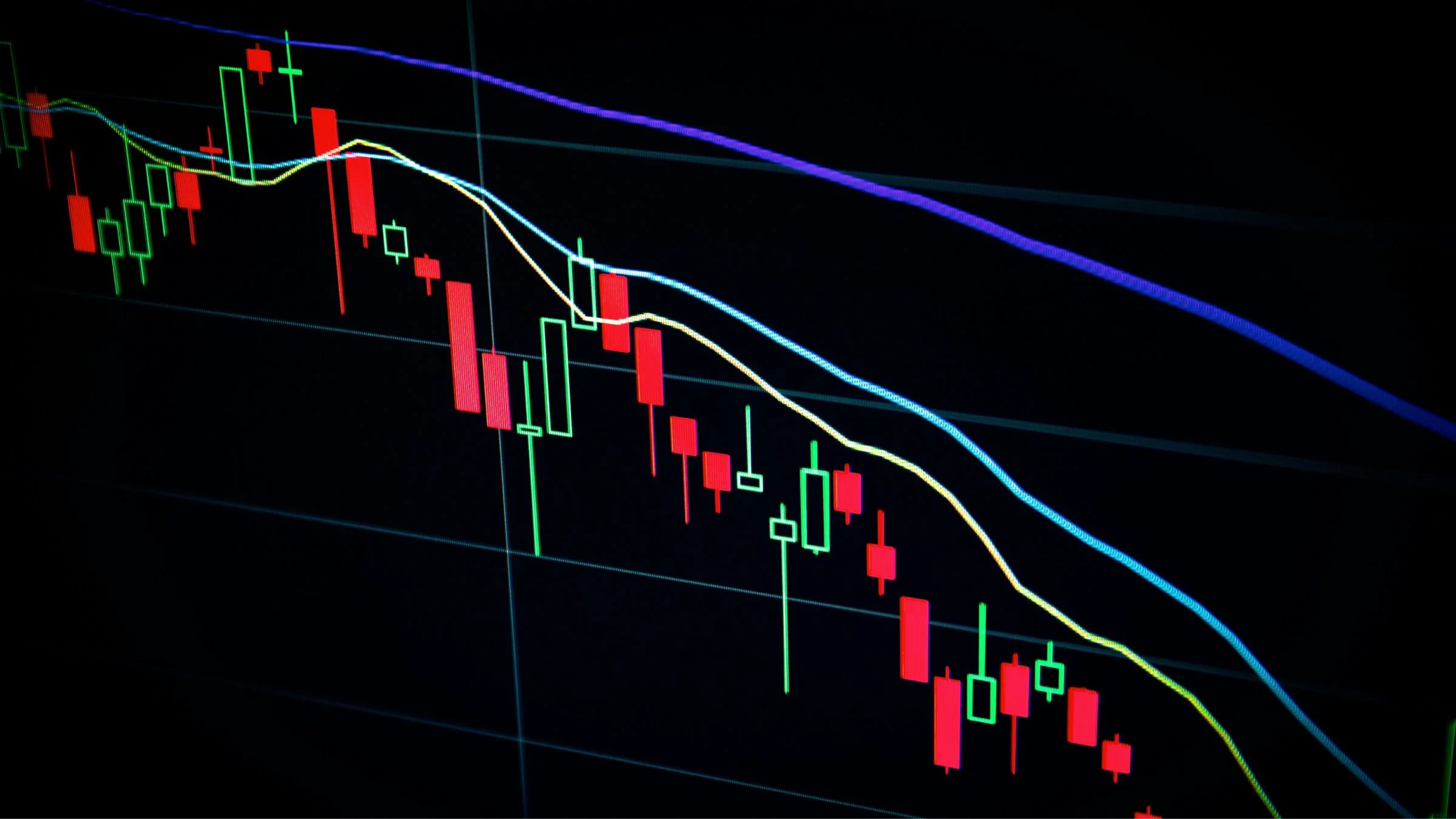 Dark trading screen with red and green candlestick chart bars and descending indicator lines.