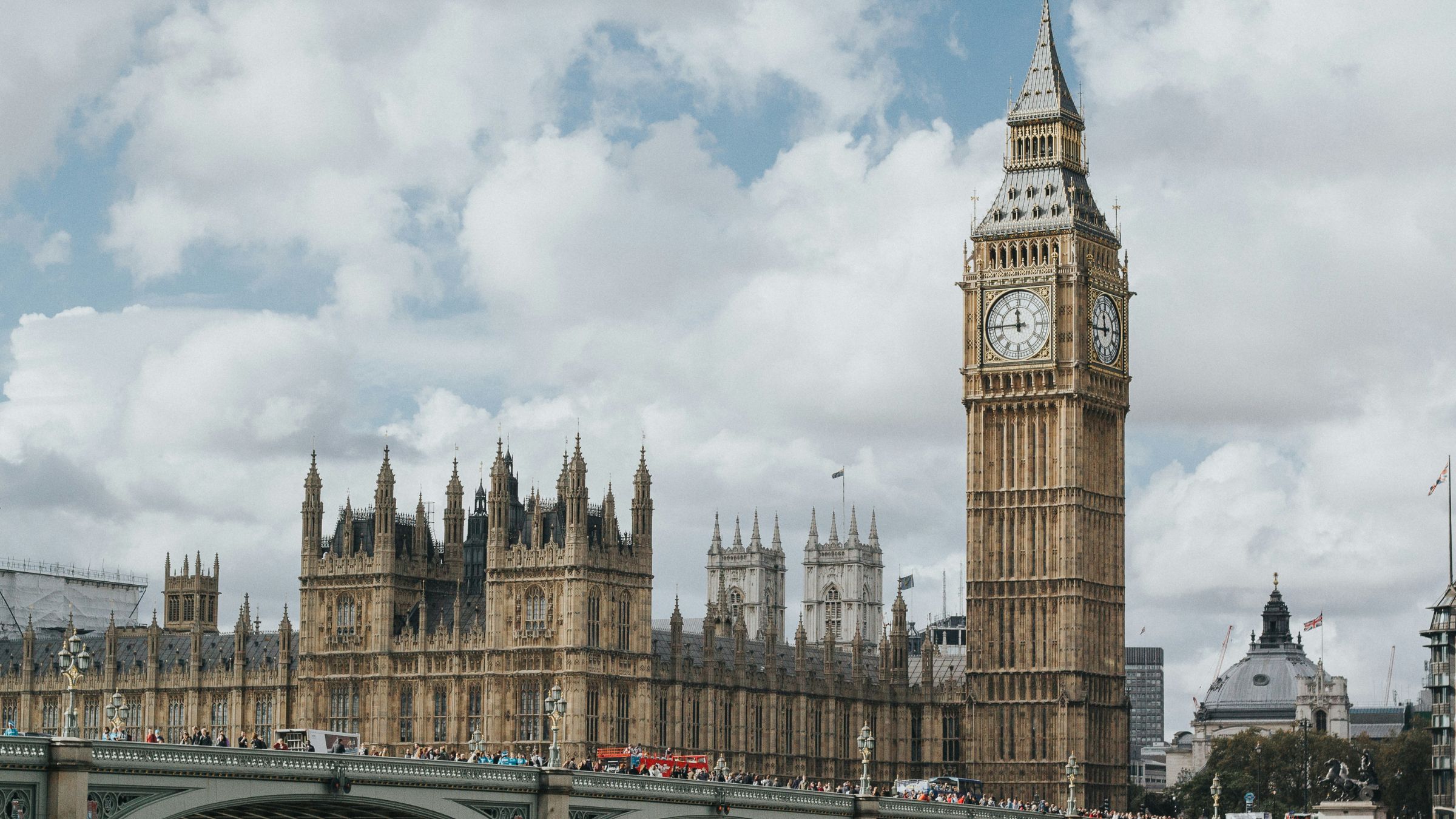 Big Ben and the Palace of Westminster seen from Westminster Bridge under a cloudy London sky.