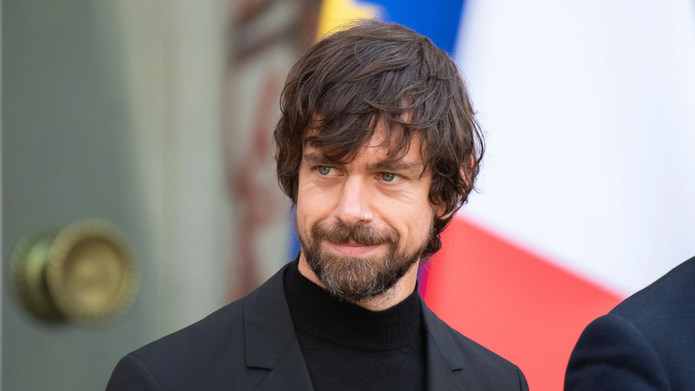 Jack Dorsey, co-founder of Twitter and CEO of Block, standing in front of a French flag at an official government venue