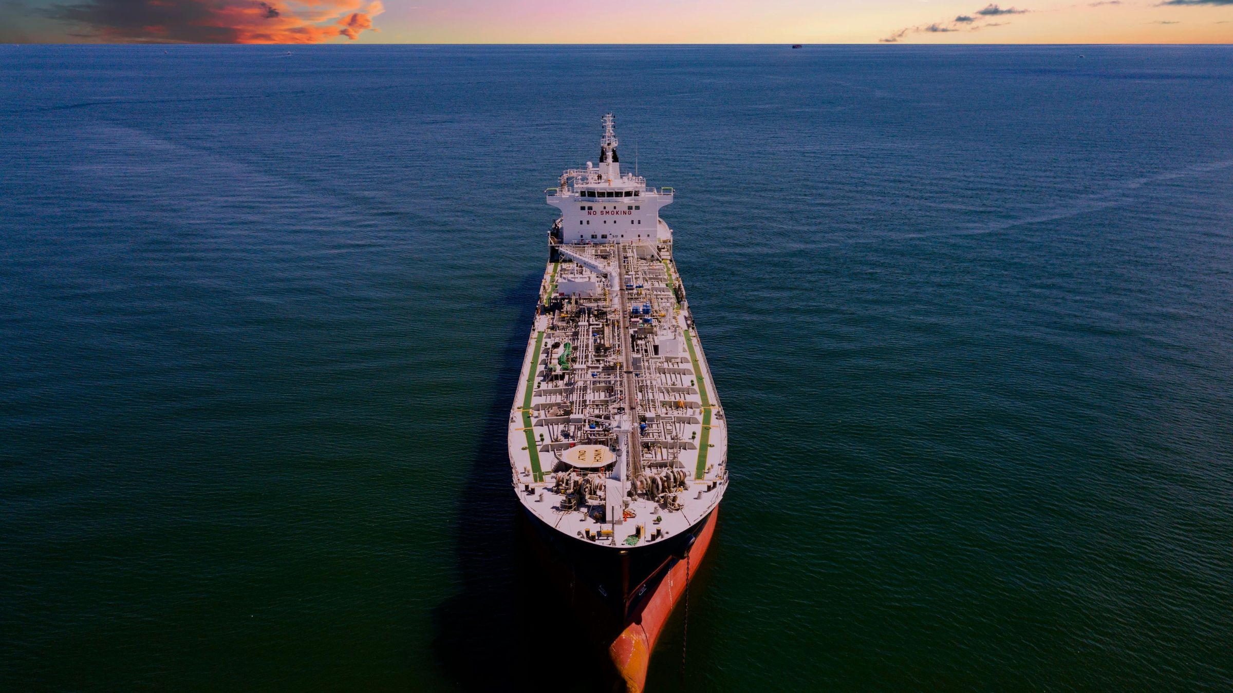 Aerial view of a large oil tanker traveling through open water at sunset.