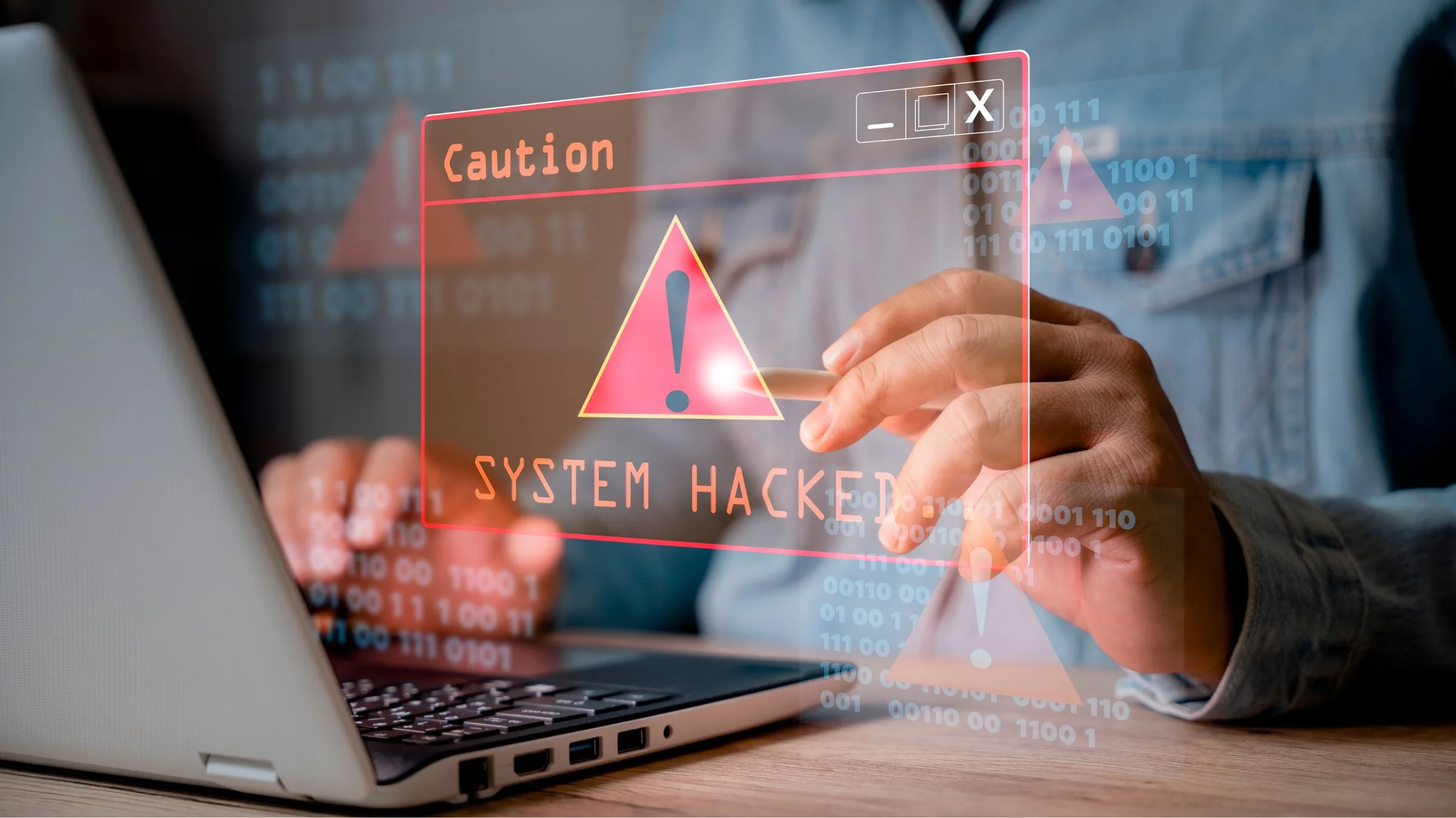 Person using a laptop with a red warning overlay reading “System Hacked” and digital alert symbols.