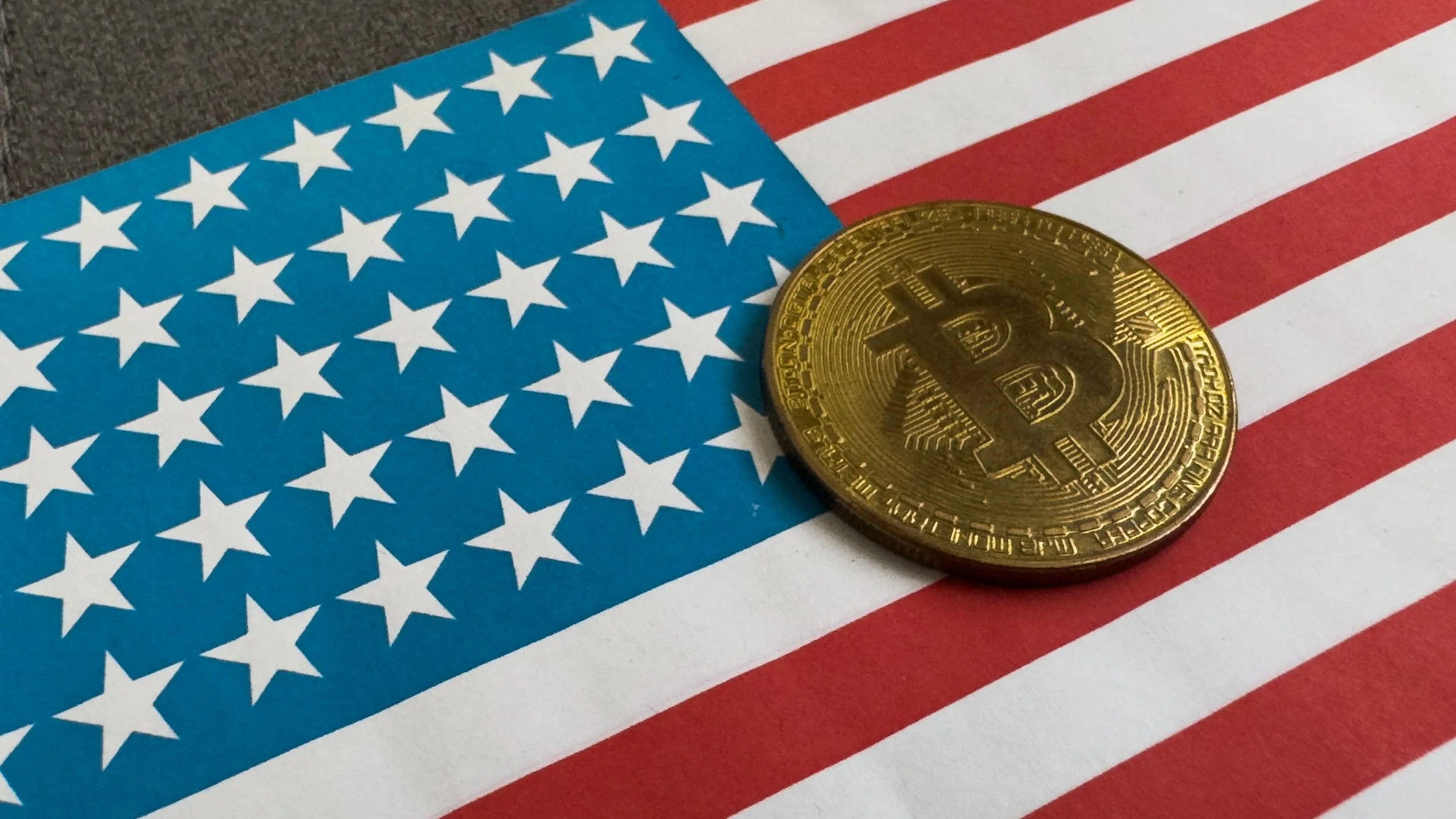 Gold Bitcoin coin resting on an American flag