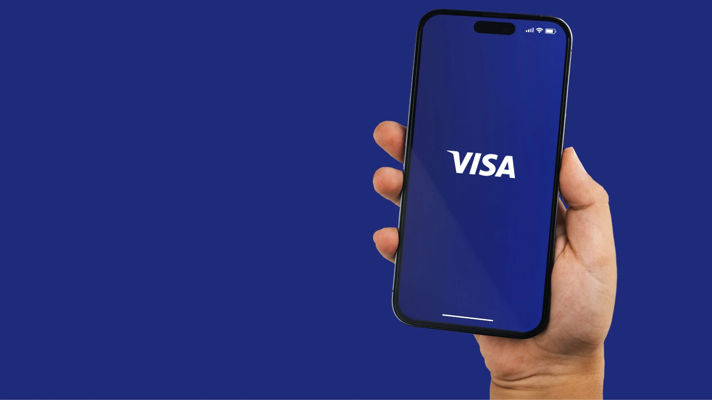 Hand holding a smartphone displaying the Visa logo on a blue screen against a plain blue background.