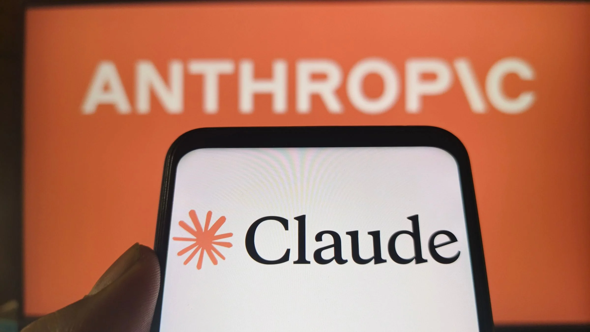 Claude AI logo on smartphone with Anthropic branding in the background