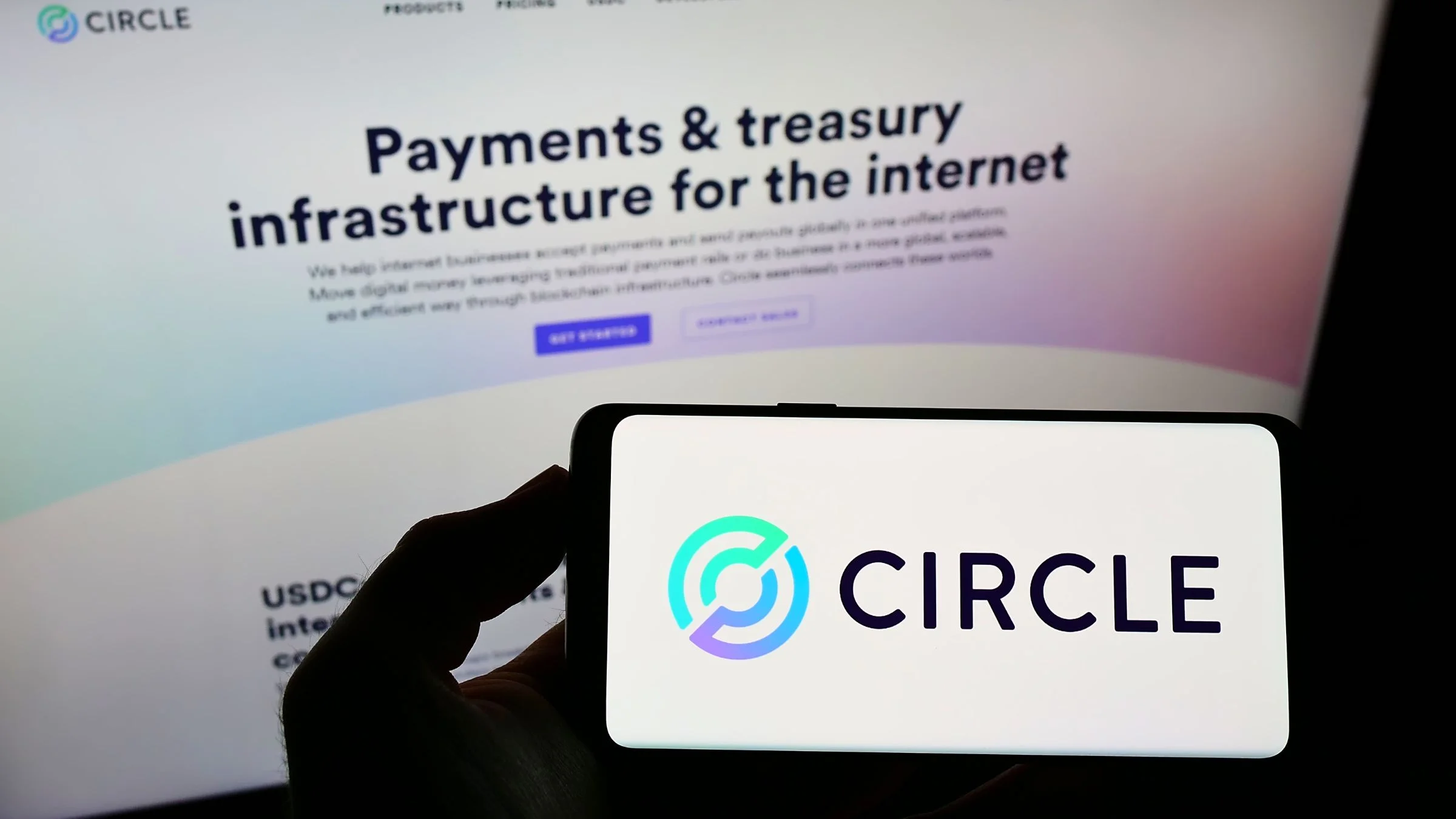 Circle fintech and USDC issuer logo shown on smartphone in front of company website