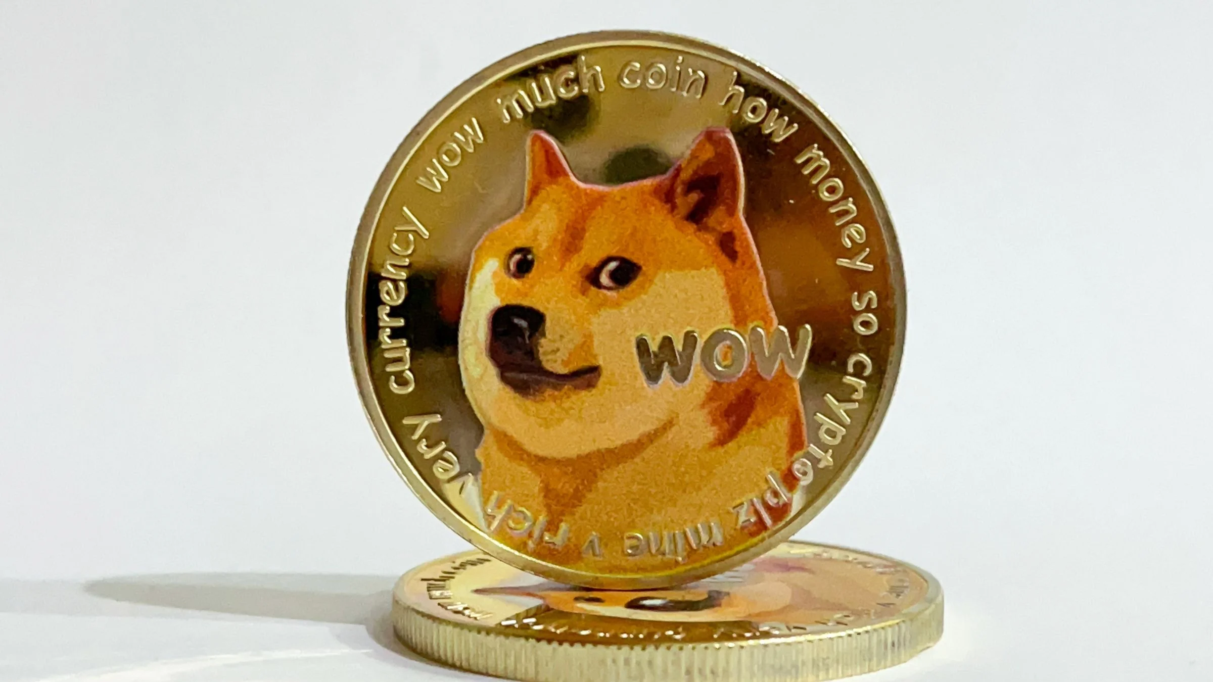 Gold Dogecoin token featuring the Shiba Inu dog and “WOW” text, standing upright on another coin.