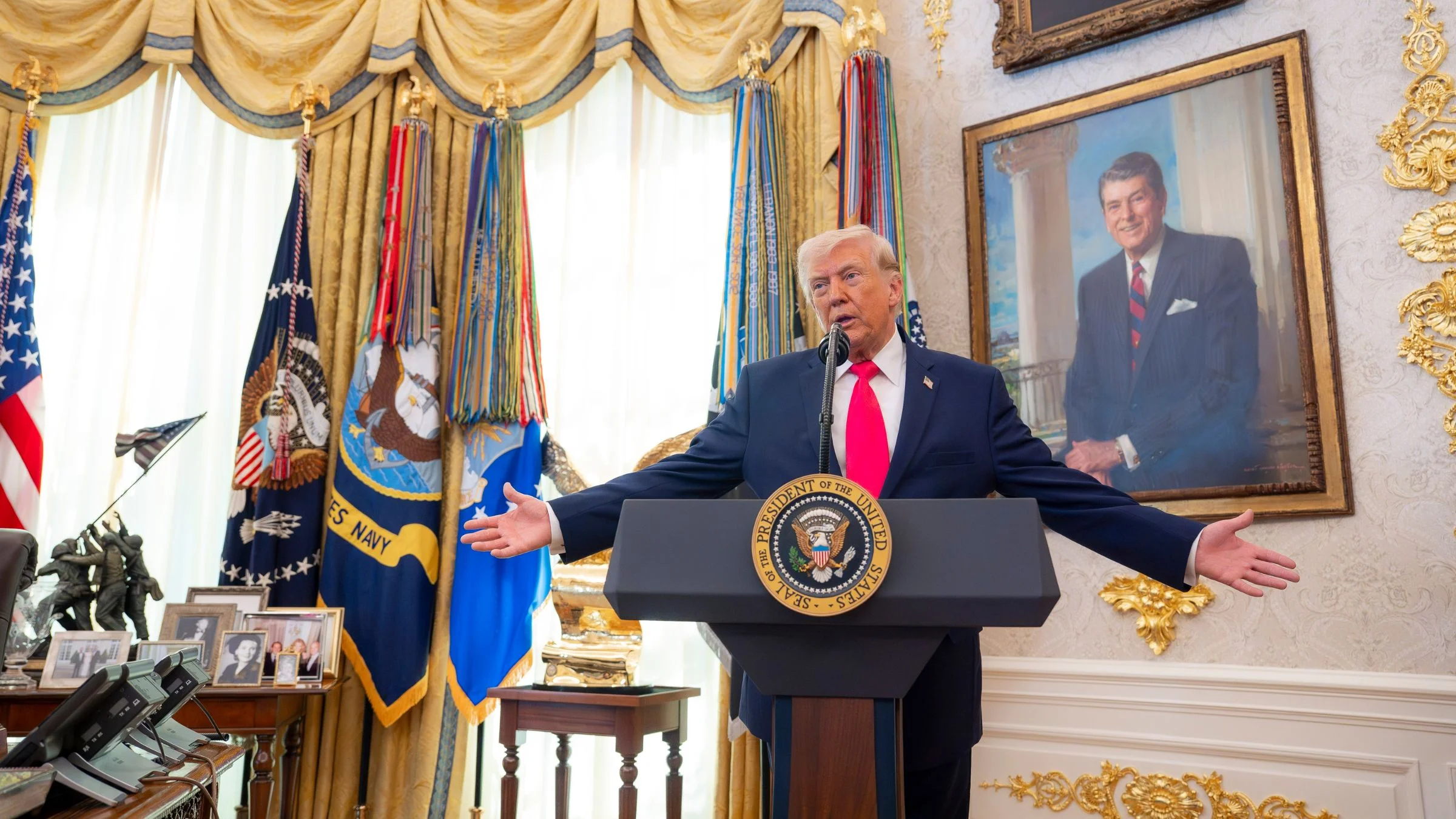 US President Donald Trump speaking at a podium inside the Oval Office
