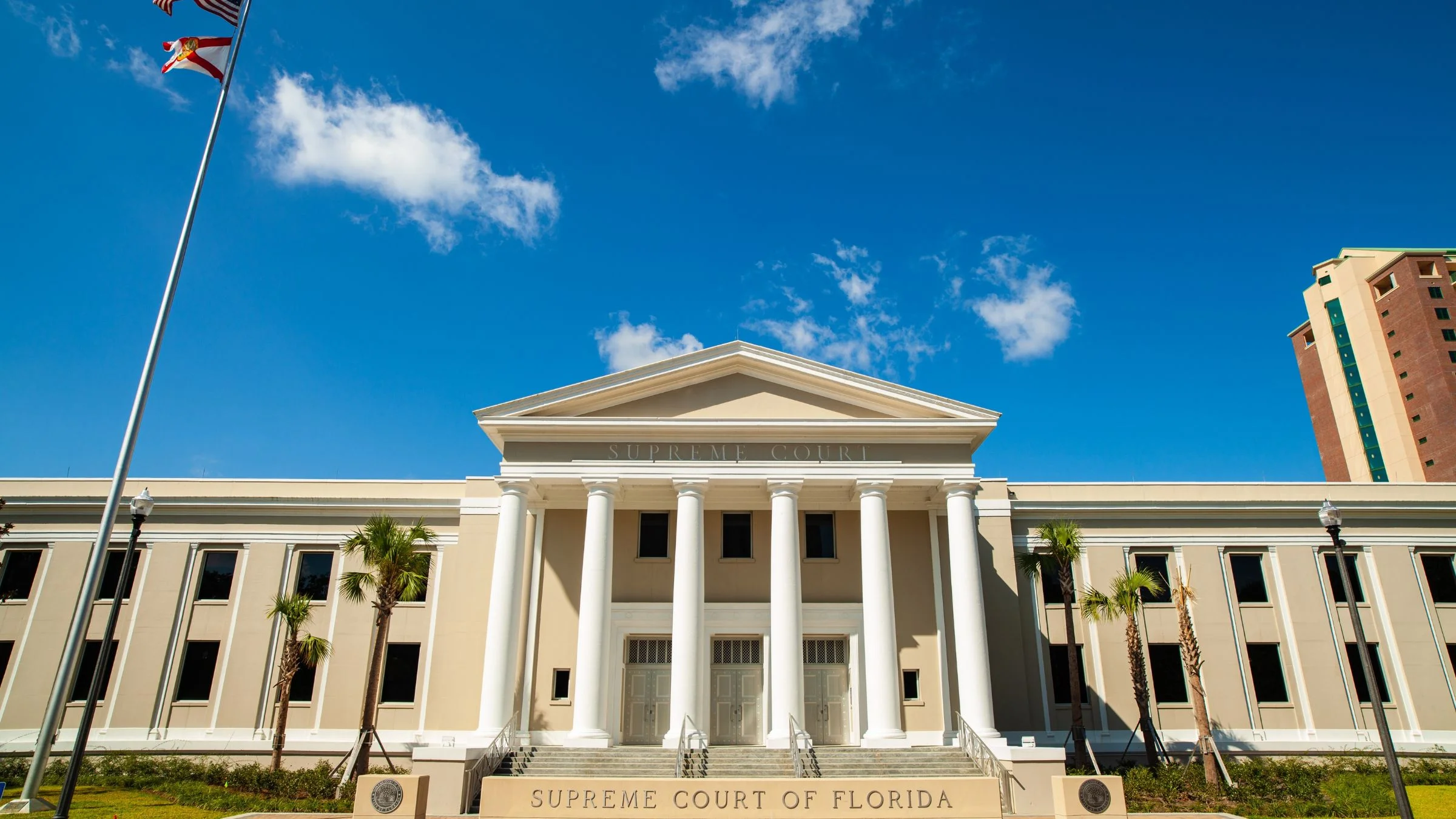 Front view of the Florida Supreme Court building with columns and US flag under blue sky