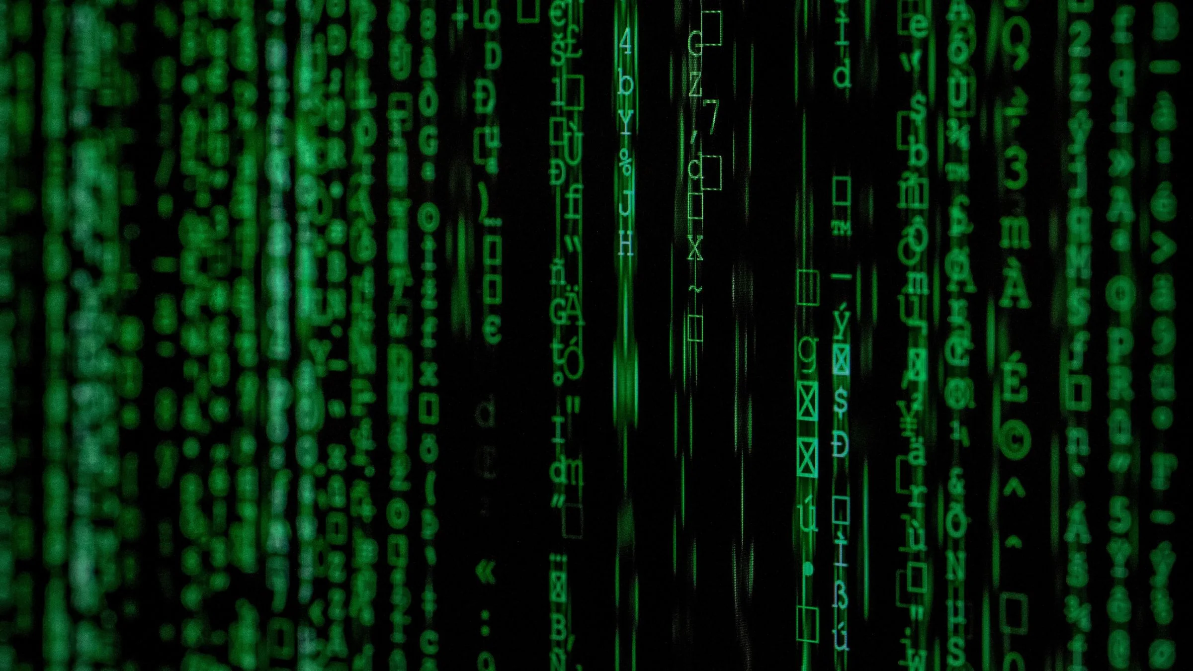 Green cascading code and symbols on a dark screen in a close-up cyber-themed image.