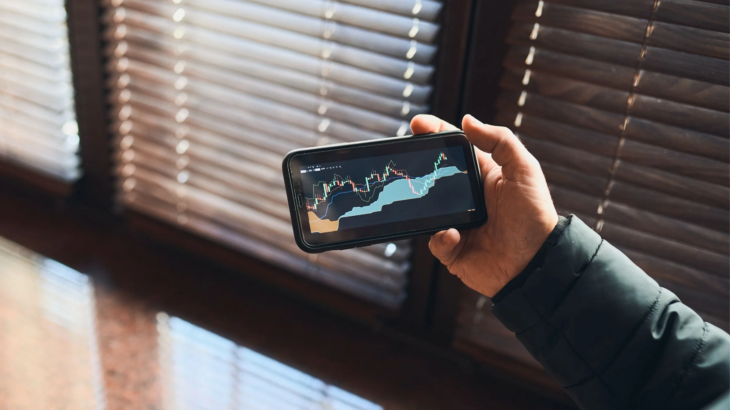 Person holding smartphone showing cryptocurrency or stock trading charts