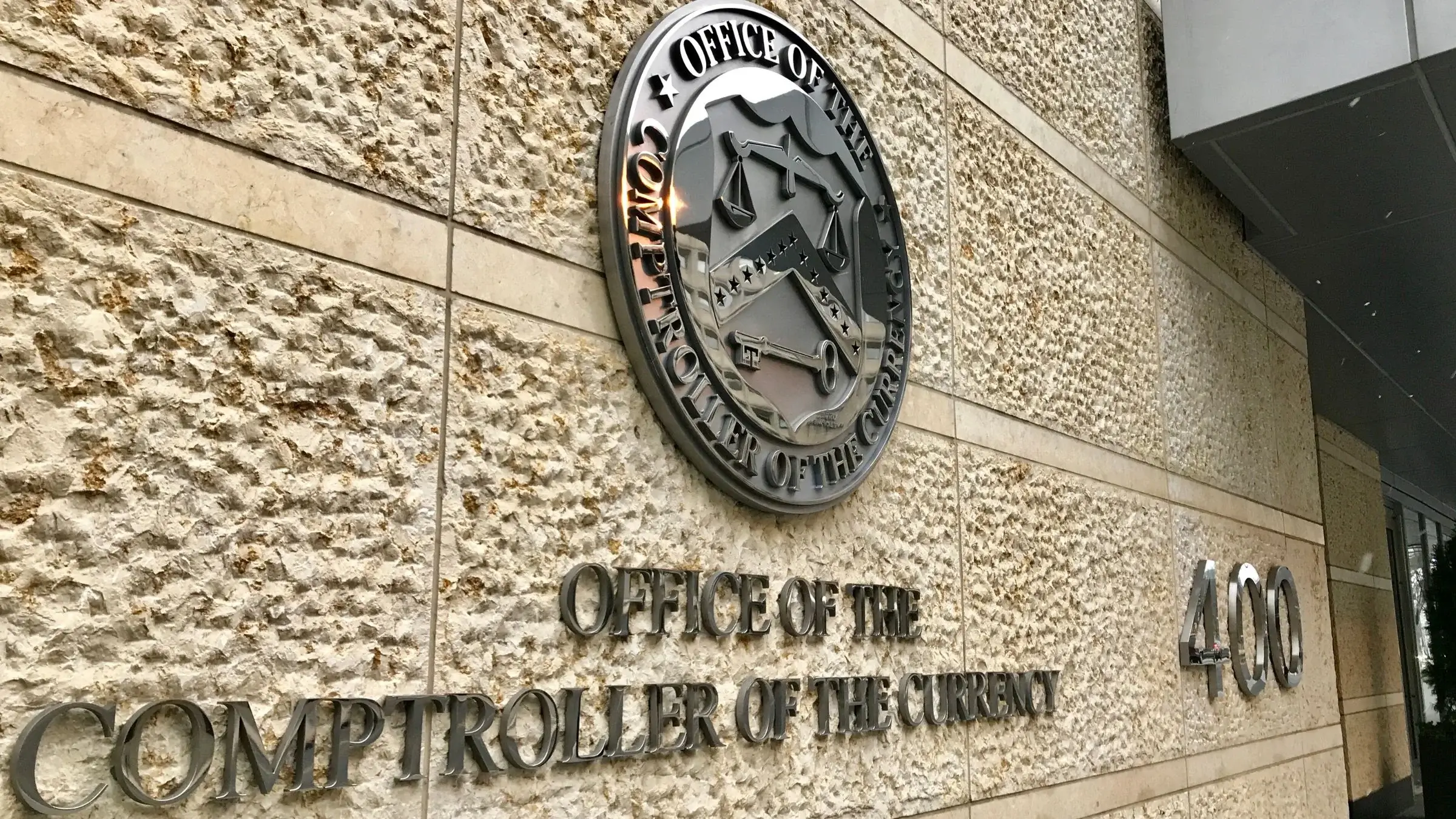 Office of the Comptroller of the Currency seal and signage on a building exterior, suitable for banking regulation coverage.