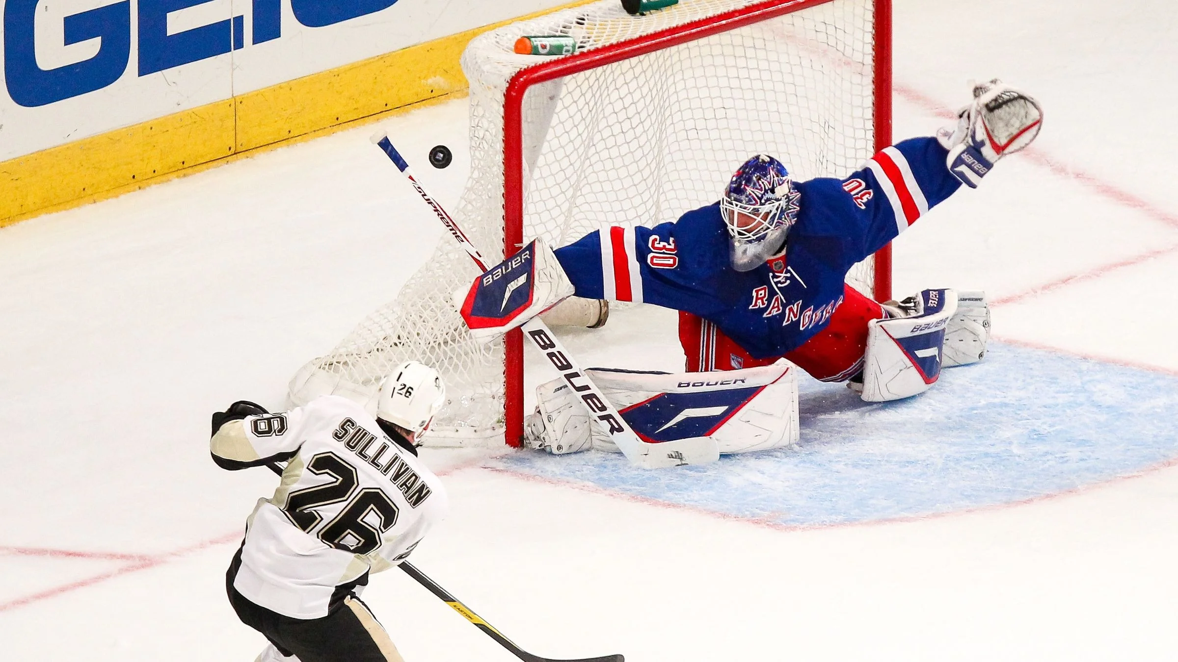 Ice hockey goalie attempting a save as opposing player shoots near the net