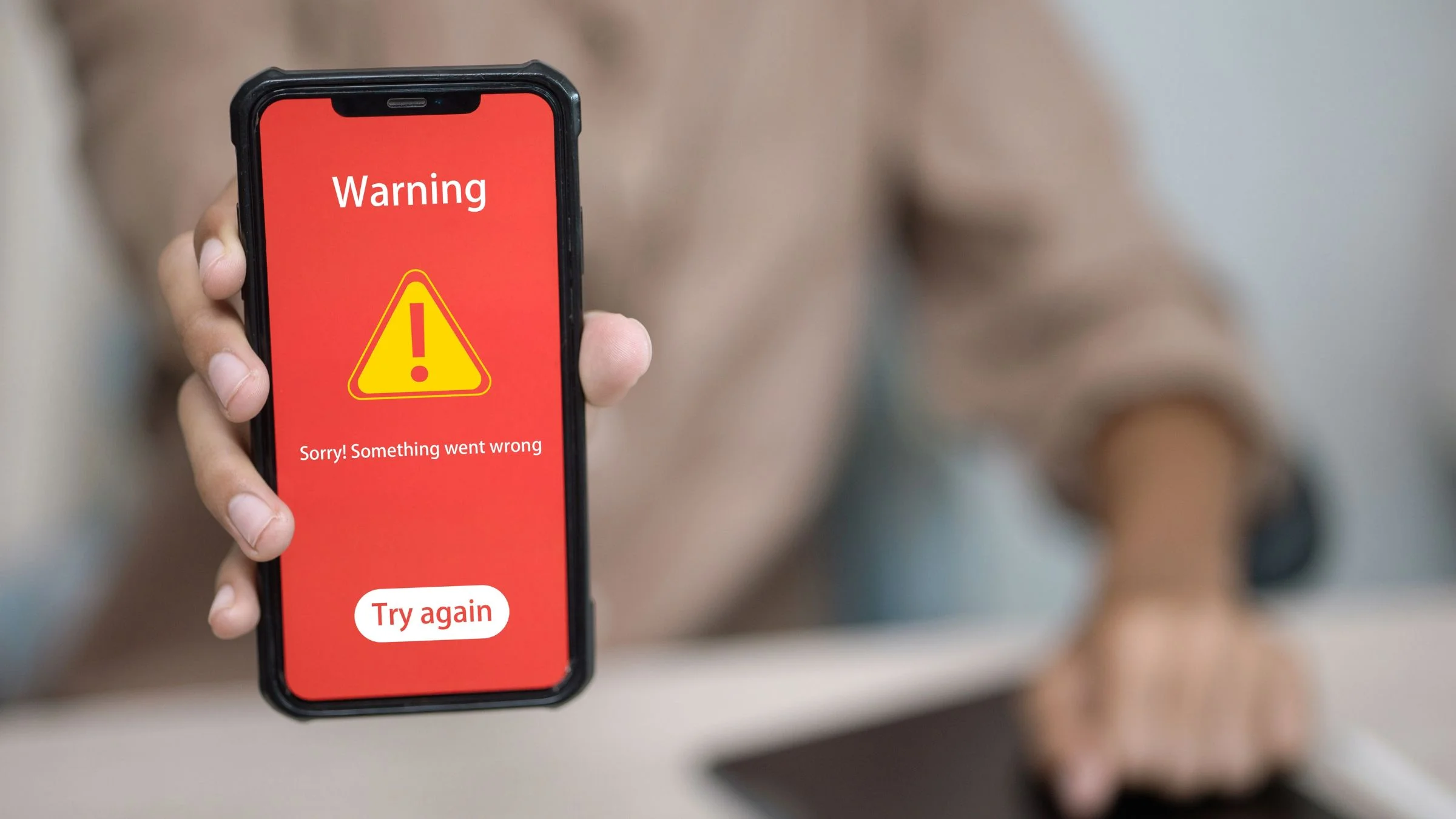 Person holding a smartphone showing a red warning screen with error message and “Try again” button.