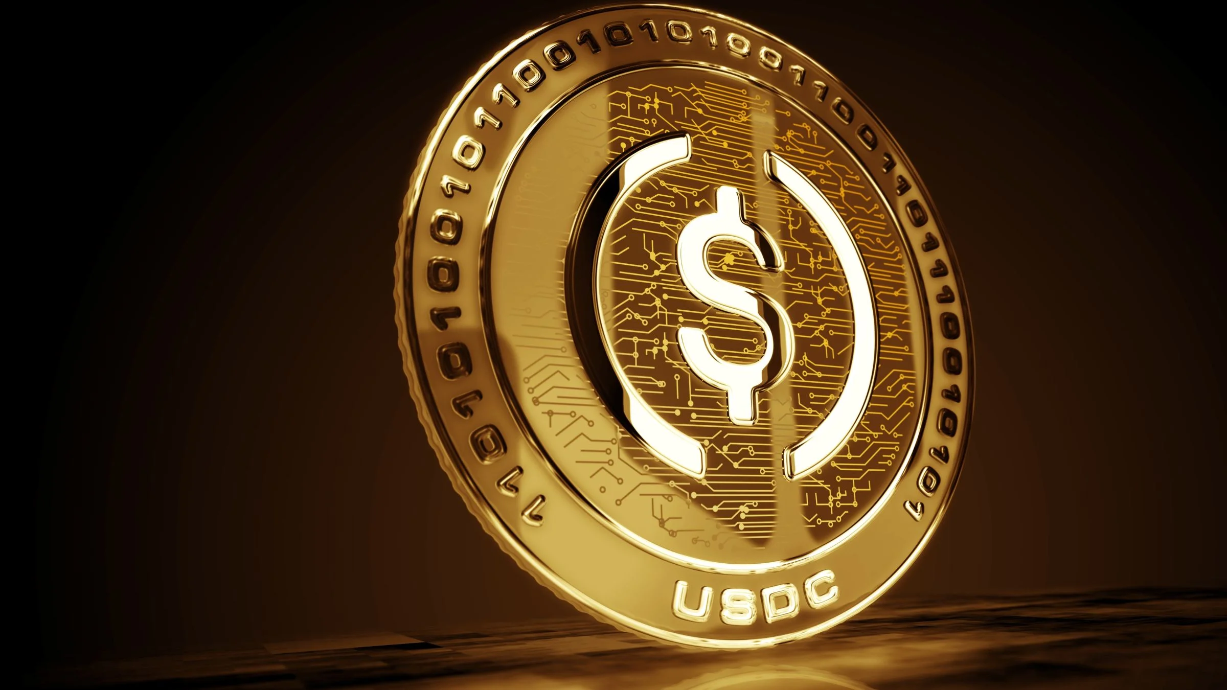 Gold USDC coin shown in close-up against a dark background, highlighting stablecoin branding and digital circuitry details.