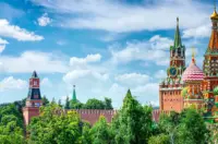 St. Basil’s Cathedral and Kremlin towers in Moscow under a bright blue sky with scattered clouds.