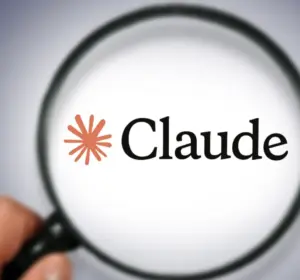 Magnifying glass held by a hand, magnifying the Claude AI logo and wordmark