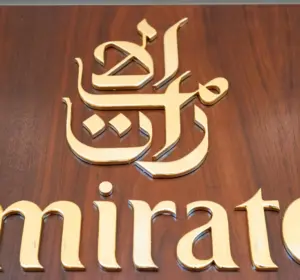 Gold Emirates airline logo and Arabic lettering mounted on a wooden wall