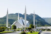 Faisal Mosque in Islamabad with four minarets and green Margalla Hills in the background.