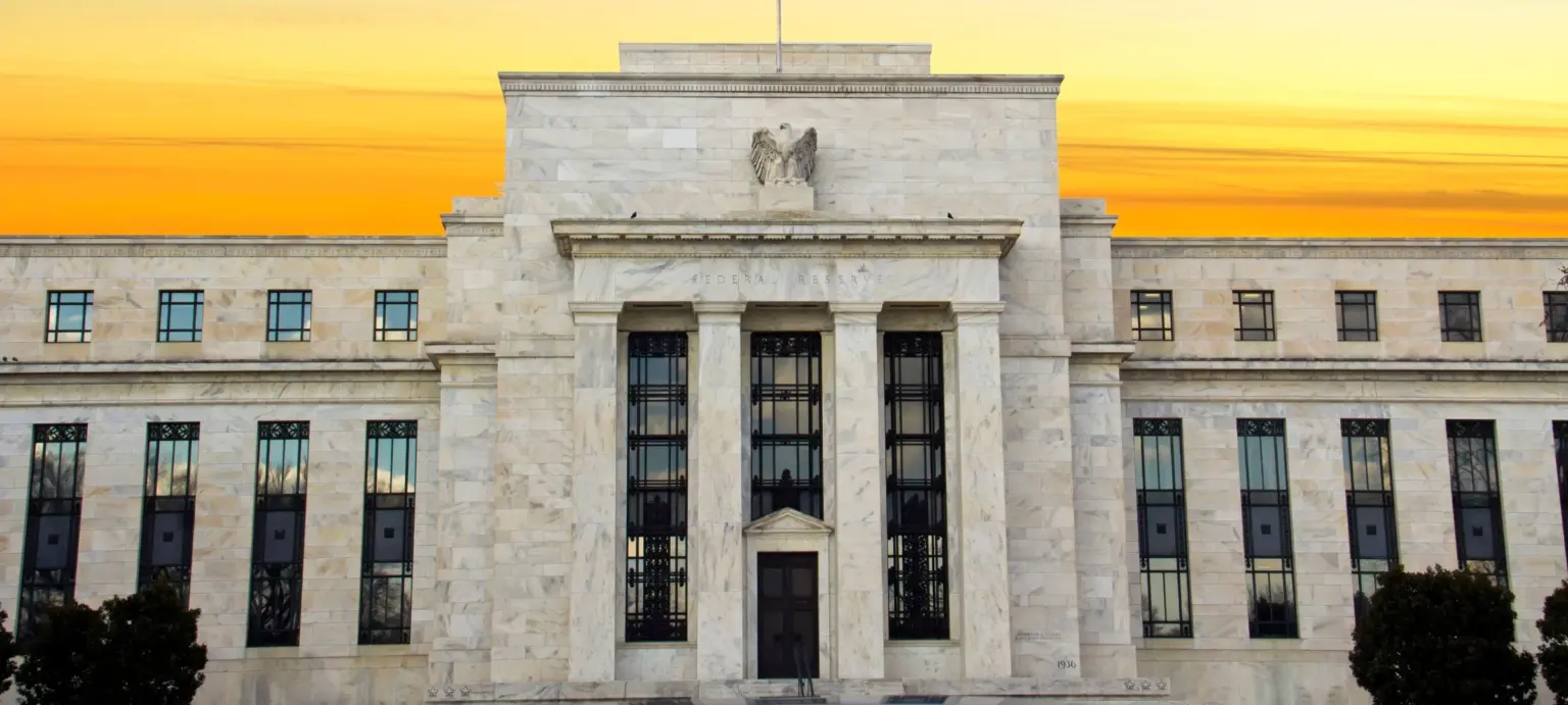 Federal Reserve building facade with marble columns and an eagle sculpture at sunset