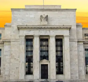 Federal Reserve building facade with marble columns and an eagle sculpture at sunset