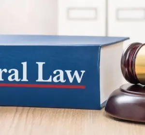 Federal law book beside a wooden judge’s gavel on a desk in a legal office.