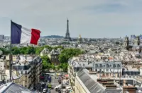 French flag flying above the Paris skyline with the Eiffel Tower in the background