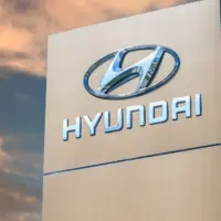 Tall Hyundai sign with chrome logo and brand name against a dramatic sunset sky.