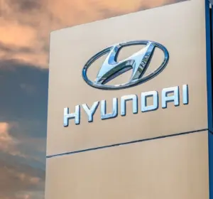Tall Hyundai sign with chrome logo and brand name against a dramatic sunset sky.