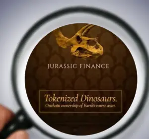 Magnifying glass held over a phone screen showing the Jurassic Finance logo and "Tokenized Dinosaurs" branding