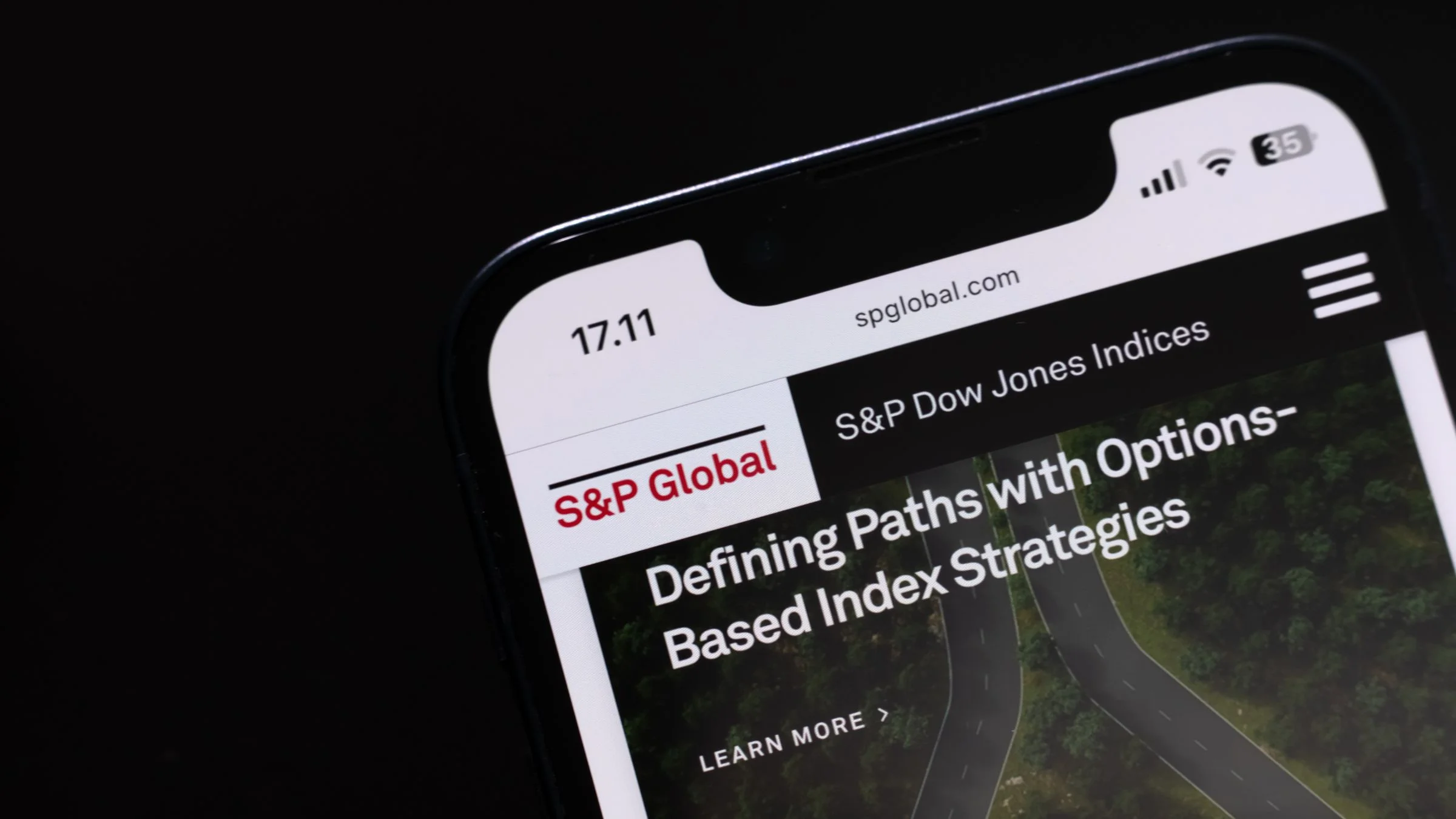 Smartphone showing the S&P Global website with S&P Dow Jones Indices branding on screen against a dark background.