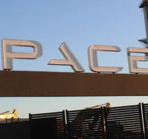 SpaceX sign at a launch facility with launch tower in the background