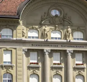 Swiss National Bank building facade with Swiss flag in the foreground.