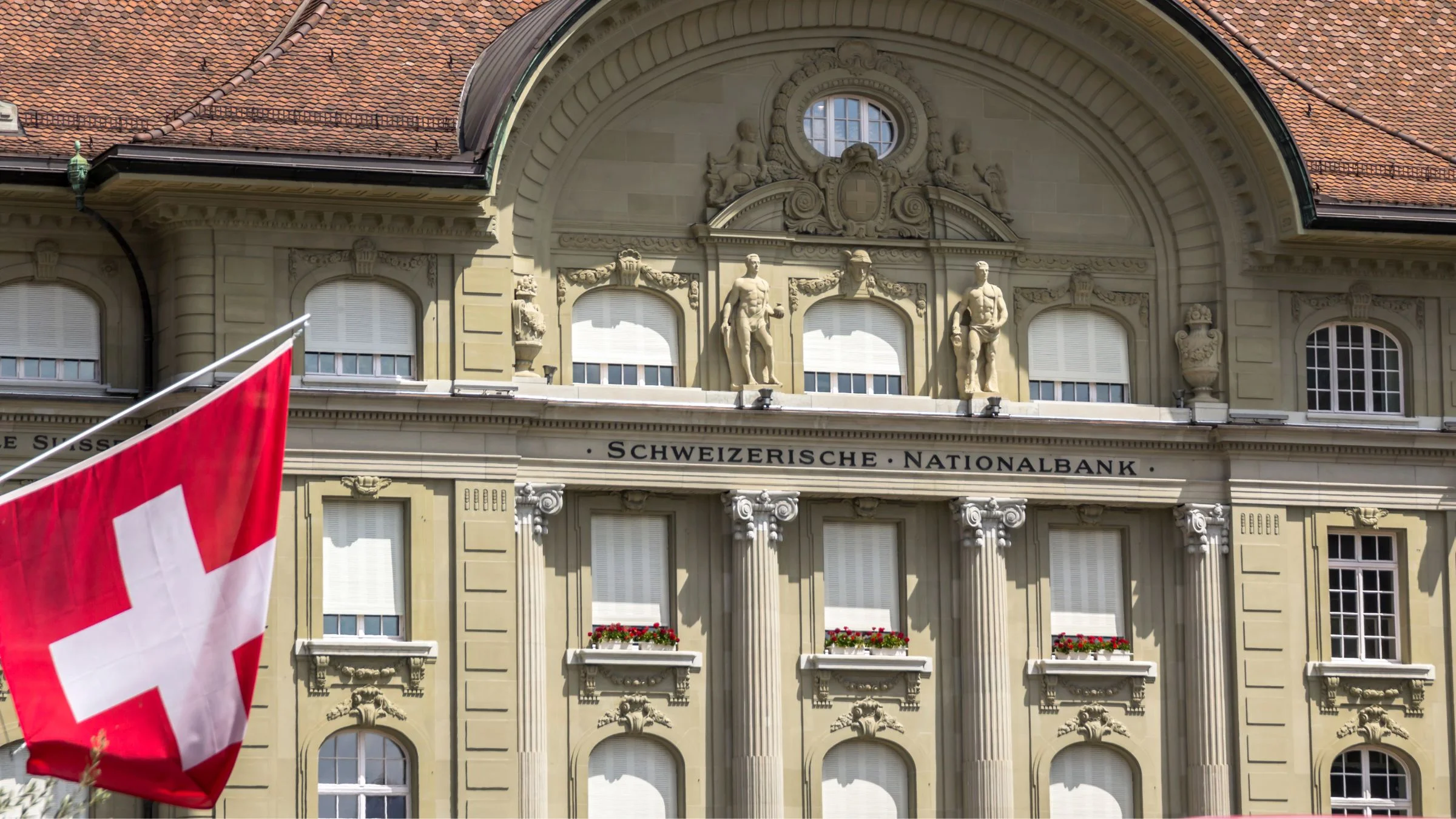 Swiss National Bank building facade with Swiss flag in the foreground.