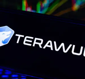 TeraWulf logo displayed on a smartphone with colorful financial trading charts in the background