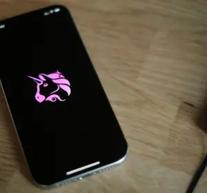 Smartphone displaying the Uniswap unicorn logo on a wooden desk