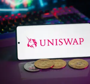 Smartphone displaying the Uniswap logo with cryptocurrency coins and trading charts visible in the background.