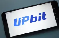 Smartphone screen displaying the Upbit logo in blue lettering against a light background.