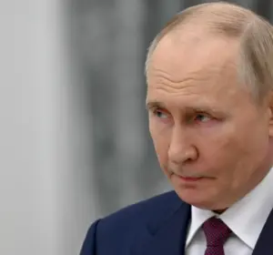 Russian political leader in a dark suit standing behind microphones at an official event.
