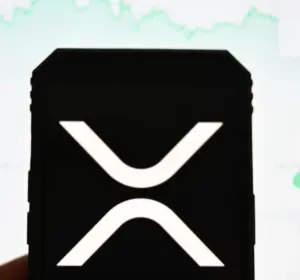 Smartphone displaying the XRP logo in front of a cryptocurrency price chart on a screen